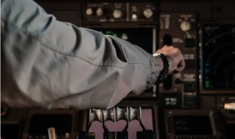 Pilot operating aircraft controls in a cockpit, focusing on throttle levers and instrument panels