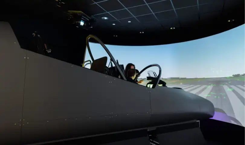 Person training in a flight simulator cockpit with a projected runway scene, showcasing realistic aviation controls and environment